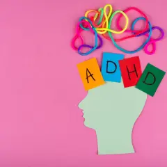 Kolorowe sznurki symbolizują chaos myśli, a kartki z literami "ADHD" umieszczone na sylwetce głowy ukazują wyzwania związane z ADHD u kobiet.