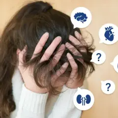Zmartwiona osoba z rękami we włosach, otoczona dymkami z ikonami narządów i znakami zapytania. Czy to hipochondryk, który ciągle martwi się o zdrowie?