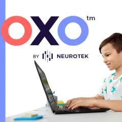 Chłopiec z uśmiechem pracuje przy laptopie, korzystając z platformy test moxo od Neurotek.