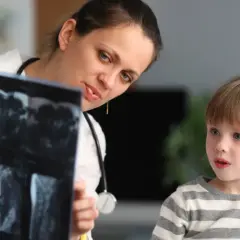 Lekarka, być może neuropsycholog, pokazuje dziecku wyniki rezonansu.