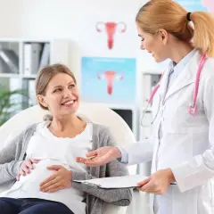 Lekarka rozmawia z ciężarną pacjentką o niedoczynności tarczycy w ciąży. Uśmiechnięta przyszła mama słucha z uwagą.