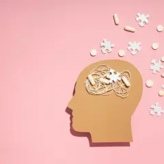Symboliczne przedstawienie problemów z koncentracją i myśli w głowie, sugerujące poszukiwanie odpowiedzi na pytanie jak leczyć ADHD. Pigułki i puzzle symbolizują leczenie.