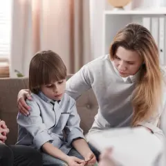 Rodzina na terapii. Matka wspiera syna, ojciec zamyślony. Sesja terapeutyczna w nurcie psychodynamicznym.