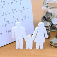 Figurki rodziny, kalendarz i słoik z monetami.