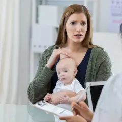 Zaniepokojona matka z niemowlęciem rozmawia z lekarzem o przyczynach jednorazowego ataku padaczki.
