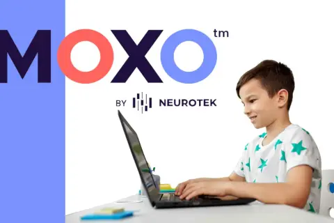 Chłopiec z uśmiechem pracuje przy laptopie, korzystając z platformy test moxo od Neurotek.