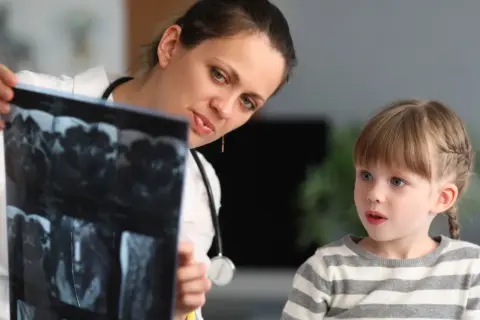 Lekarka, być może neuropsycholog, pokazuje dziecku wyniki rezonansu.