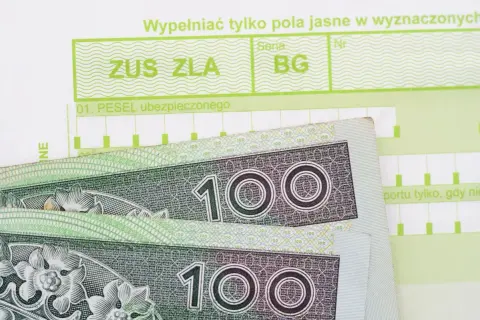 Zwolnienie lekarskie ZUS ZLA z polami na PESEL i kodami cyfrowymi, obok banknoty 100 zł.