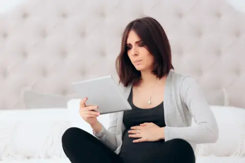 Przerażona ciężarna szuka informacji o tokofobii, czyli lęku przed porodem, na tablecie.