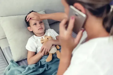 Chora l4 na dziecko, mama sprawdza temperaturę i dzwoni po pomoc.
