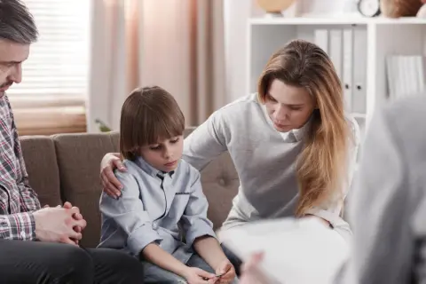 Rodzina na terapii. Matka wspiera syna, ojciec zamyślony. Sesja terapeutyczna w nurcie psychodynamicznym.