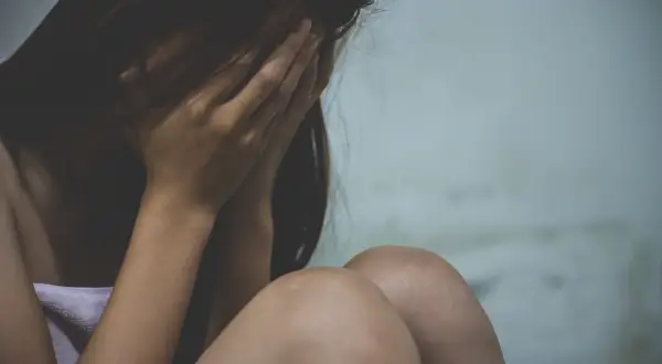 Kobieta ukrywa twarz w dłoniach, przygnębiona. Może to być związane z wypowiedzeniem umowy o pracę a zwolnieniem lekarskim od psychiatry.