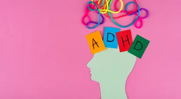 Kolorowe sznurki symbolizują chaos myśli, a kartki z literami "ADHD" umieszczone na sylwetce głowy ukazują wyzwania związane z ADHD u kobiet.