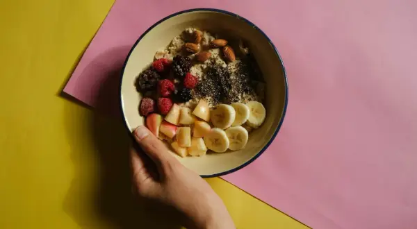Miseczka owsianki z owocami i orzechami, idealna na śniadanie wspierające dietę bogatoresztkową.