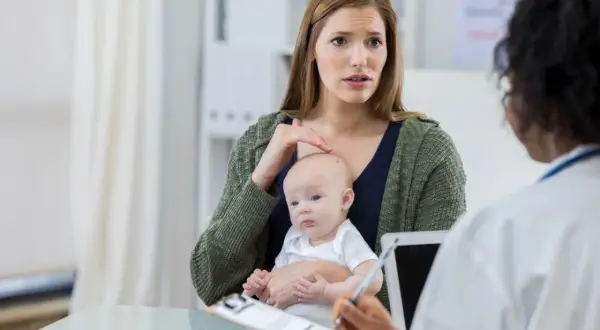 Zaniepokojona matka z niemowlęciem rozmawia z lekarzem o przyczynach jednorazowego ataku padaczki.