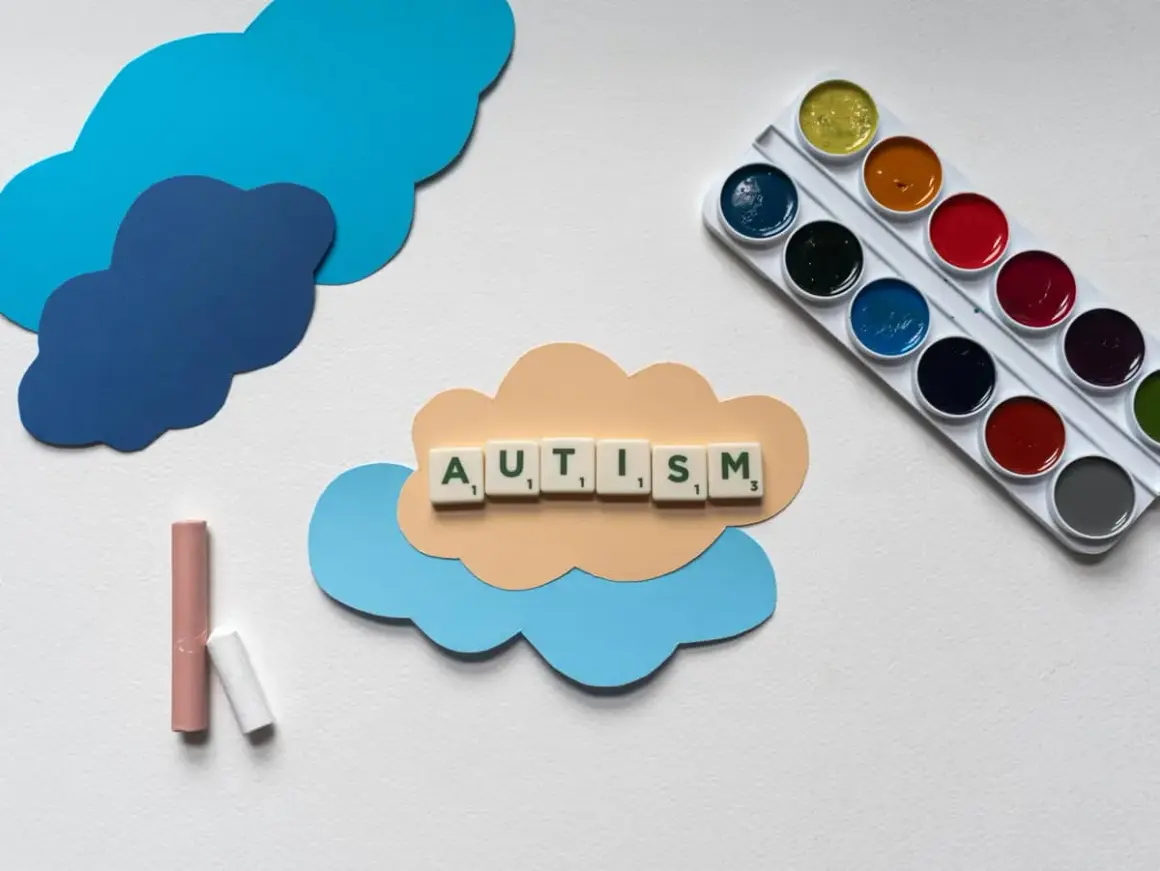 Litery układają słowo AUTISM na chmurce. Obok kredki i farby. Dzieci z autyzmem wysokofunkcjonującym mogą rozwijać się twórczo.