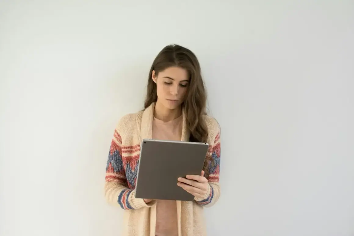 Kobieta w swetrze z kolorowym wzorem korzysta z tabletu, szukając informacji o psychiatra online L4.