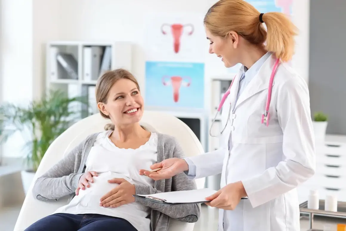 Lekarka rozmawia z ciężarną pacjentką o niedoczynności tarczycy w ciąży. Uśmiechnięta przyszła mama słucha z uwagą.