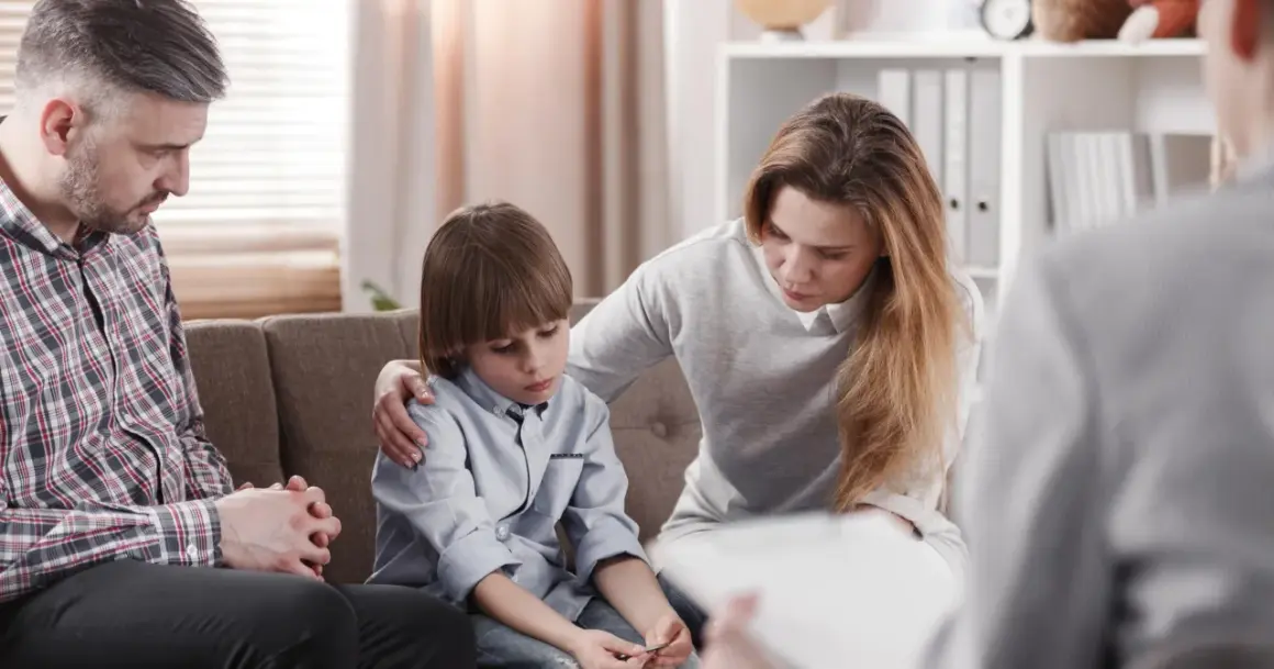 Rodzina na terapii. Matka wspiera syna, ojciec zamyślony. Sesja terapeutyczna w nurcie psychodynamicznym.