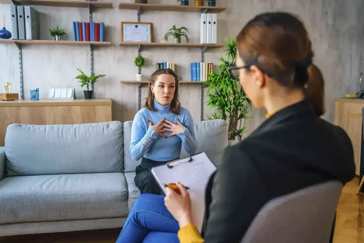 Kobieta na kanapie opowiada o swoich problemach, a terapeuta notuje. To sesja, która może pomóc zrozumieć, cbt co to.