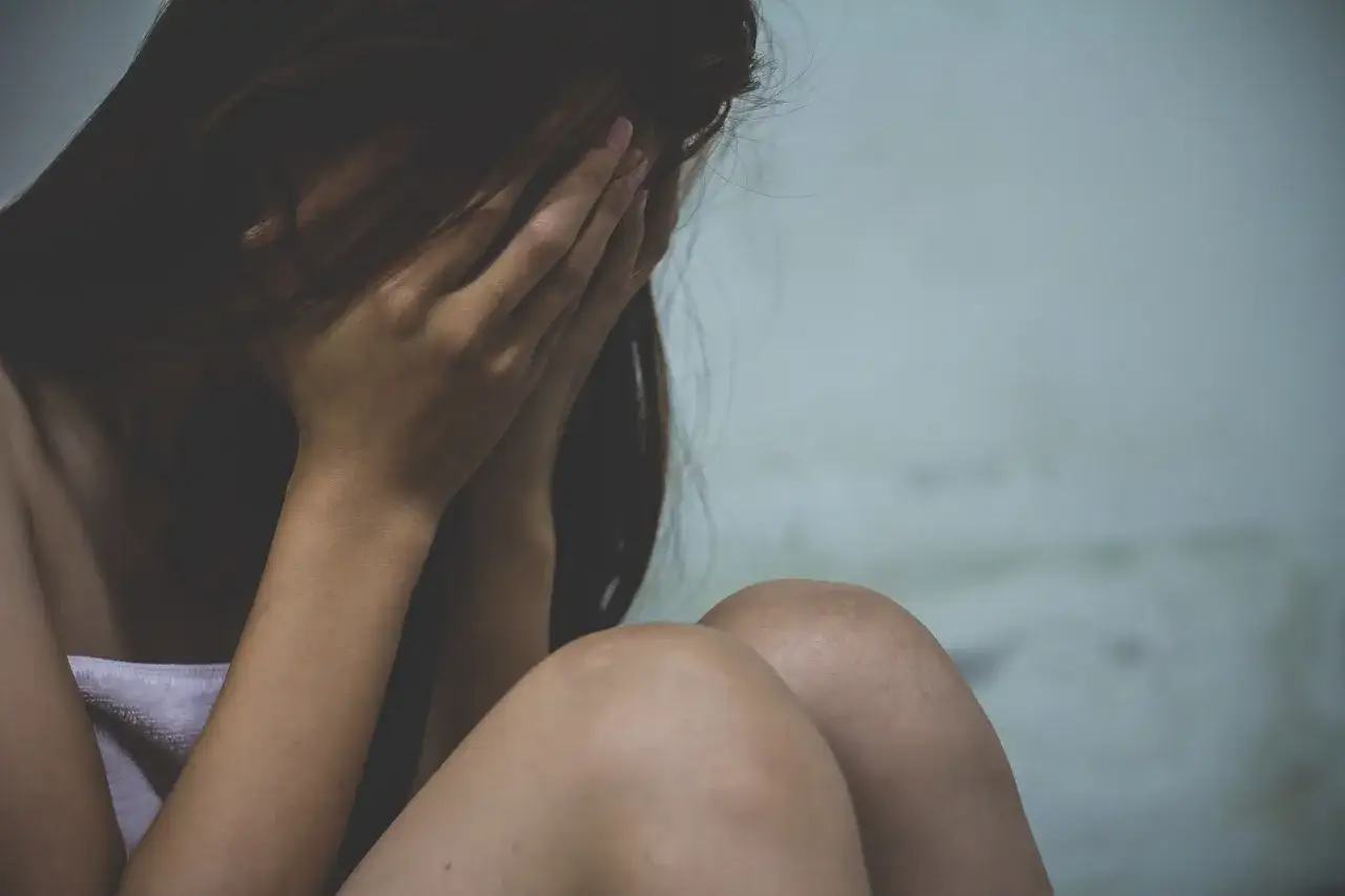 Zrozpaczona kobieta ukrywa twarz w dłoniach. Może to symbolizować trudności związane z wypowiedzeniem umowy o pracę a zwolnieniem lekarskim od psychiatry.