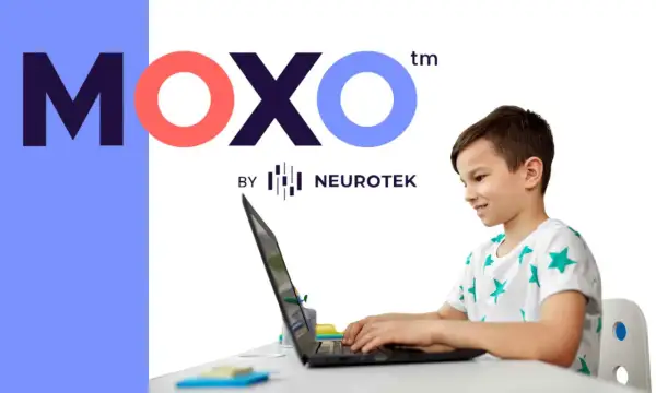Chłopiec z uśmiechem pracuje przy laptopie, korzystając z platformy test moxo od Neurotek.