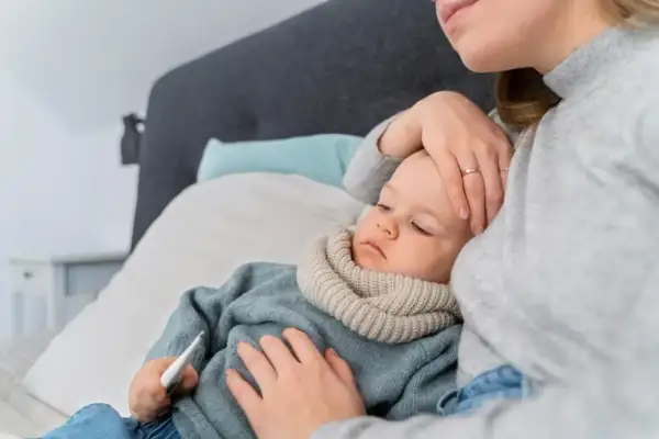 Matka czule opiekuje się chorym dzieckiem, które ma gorączkę. Lekarz wystawił zwolnienie na opiekę nad członkiem rodziny.