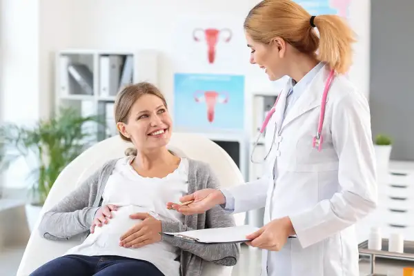 Lekarka rozmawia z ciężarną pacjentką o niedoczynności tarczycy w ciąży. Uśmiechnięta przyszła mama słucha z uwagą.