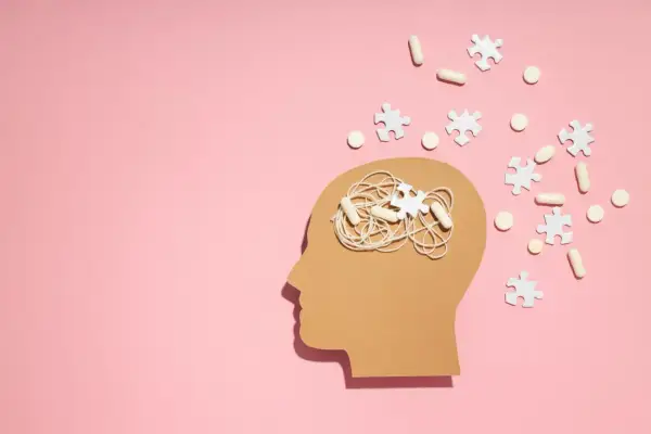 Symboliczne przedstawienie problemów z koncentracją i myśli w głowie, sugerujące poszukiwanie odpowiedzi na pytanie jak leczyć ADHD. Pigułki i puzzle symbolizują leczenie.